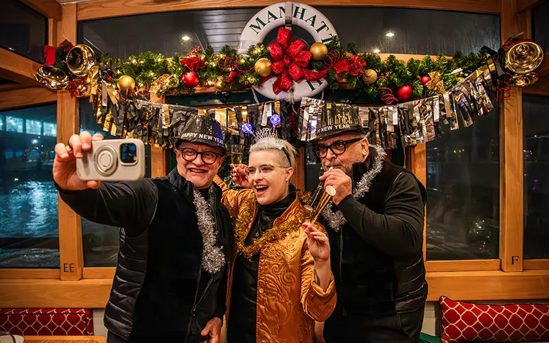 NewYear11 Two men and a woman taking a selfie on a boat on New Year's Even in NYC