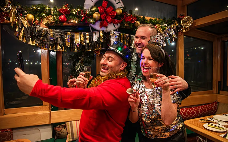 NewYear12 Group of three friends taking a selfie on in the New Year's Eve clothing with decorations in the background