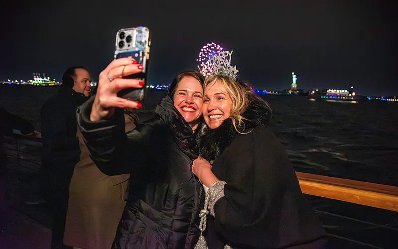 NewYear16 Two women taking a selfie with the Statue of Liberty behind them and fireworks on New Year's Eve