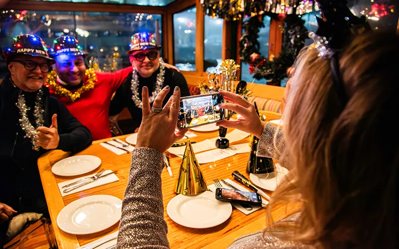 NewYear3 Woman taking a photo of three male friends with New Year's Eve hats on