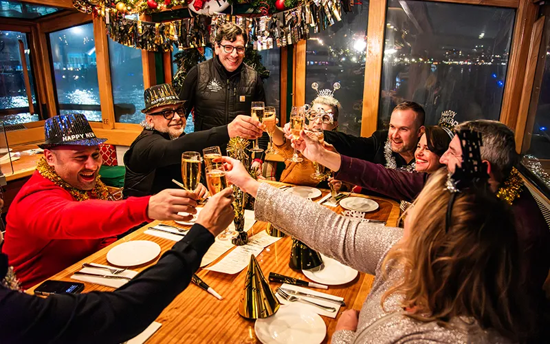 NewYear6 Group of friends at a table on a yacht holding up their champagne glasses on New Year's Eve