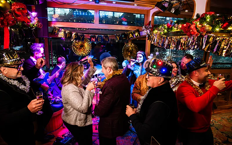 NewYear9 Guests dancing in the grand salon of yacht Manhattan II with a band playing in the background and New Year's Eve decorations all around