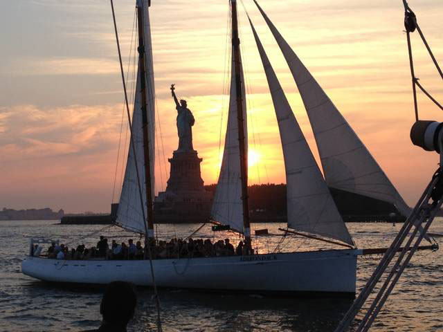 Full boat photo of schooner Adirondack sailing and seeing the Statue of Liberty between the Main Sail and the Foresail