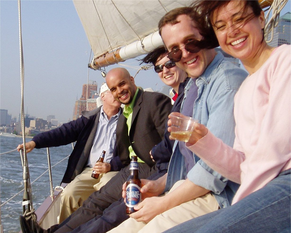 Smiling group of friends holding their drinks up as the sail aboard the Schooner Adirondack 