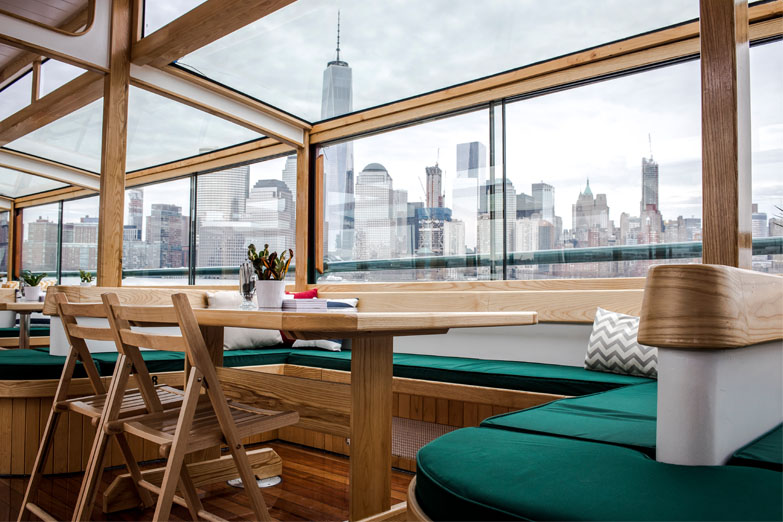 Private table inside yacht Manhattan II with the grand windows and NYC Skyline outside the windows