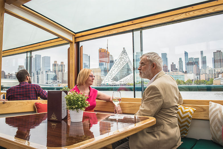 Older couple sitting at a private table looking out the grand windows with the skyline in the background on an Architecture Tour