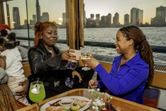 Friends enjoying holiday drinks aboard the yacht Manhattan II at private table with holiday decor