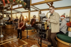 Live band playing holiday music on Yacht Manhattan II with holiday decor in the background