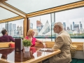 Older couple sitting at a private table looking out the grand windows with the skyline in the background on an Architecture Tour