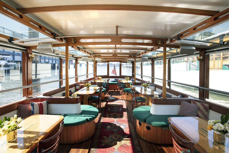 Interior photo of the main salon showcasing the aft portion of the yacht and the set up of tables