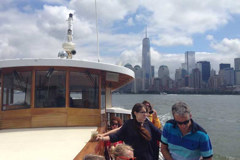 Friends on the bow of yacht Manhattan for a sightseeing cruise in NY Harbor with the NYC Skyline in the background 