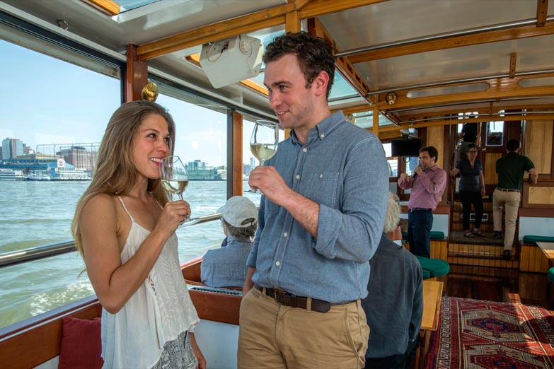 Couple standing in the main salon enjoying a glass of Champagne while on a Sunset Cruise
