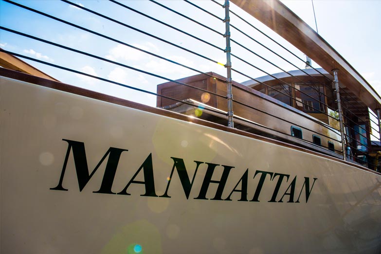 Bow show of the name of the Yacht Manhattan in hunter green coloring