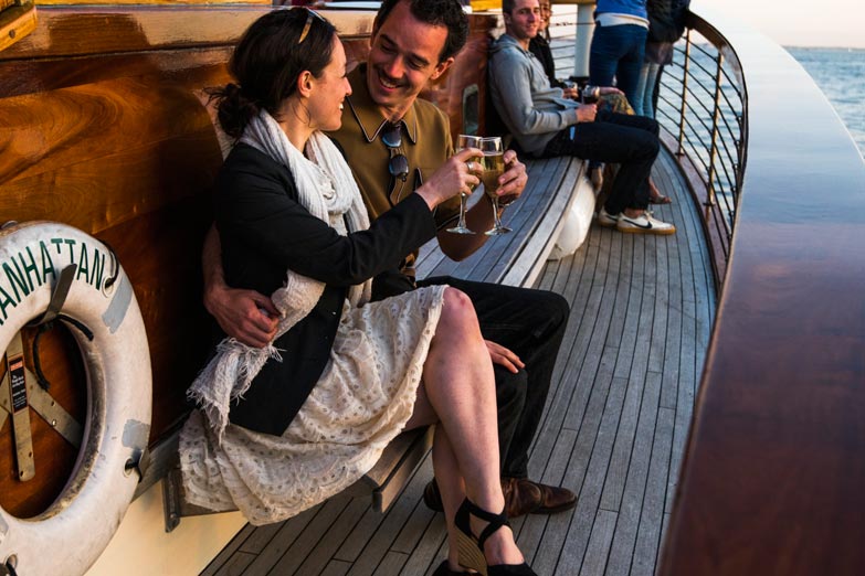Young couple sitting on the outside of the yacht Manhattan while on an afternoon cruise enjoying beverages